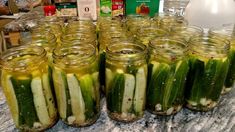 several jars filled with pickles sitting on top of a counter