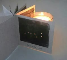 a lit candle is in the corner of a paper box that looks like an origami bird