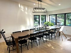 a dining room table and chairs in front of large windows with lots of natural light