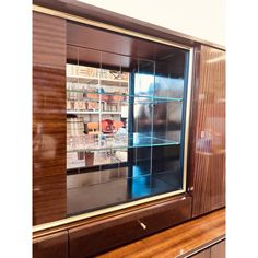 an empty display case with glass doors on the front and sides, in a wood paneled room