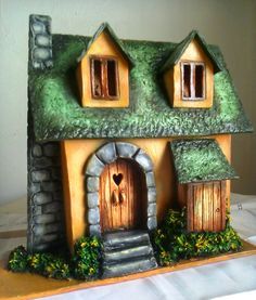 a small house made out of clay with moss growing on the roof