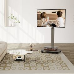 a flat screen tv mounted to the side of a wall next to a couch and coffee table