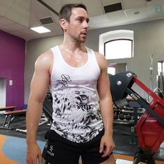 a man standing in front of a gym machine with his hands on his hips and looking at the camera