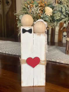 a wooden box with two hearts and a bow tie on it sitting on a table