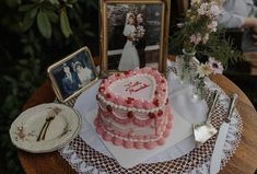 a heart shaped cake sitting on top of a table next to a couple's pictures