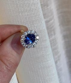 a hand holding a blue and white diamond ring