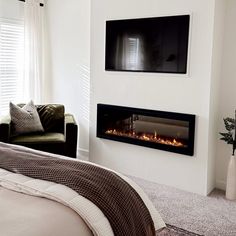 a bedroom with a bed and a fireplace in the wall next to a couch, chair and television