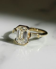 an emerald cut diamond ring with baguettes on the side