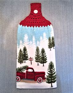 an oven mitt with a red truck and trees on it, hanging from the wall