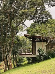 a small house in the middle of some trees and grass with an open porch on one side