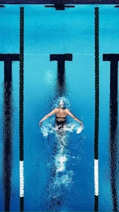 a woman swimming in a pool with her back turned to the camera and looking down