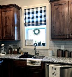 a kitchen with black and white checkered blind in the window above the dishwasher