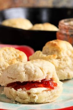 two biscuits with jam on them sitting on a plate next to a pot of jelly