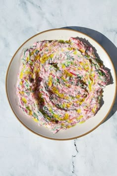 a white plate topped with food on top of a marble countertop next to a knife and fork