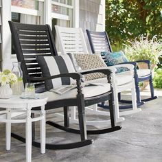 four rocking chairs on a porch with pillows and vases sitting on the coffee table