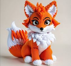 an orange and white knitted fox sitting on top of a table