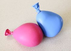 two blue and pink balloons sitting on top of a white countertop next to each other