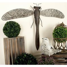 a dragonfly statue sitting on top of a wooden table next to potted plants