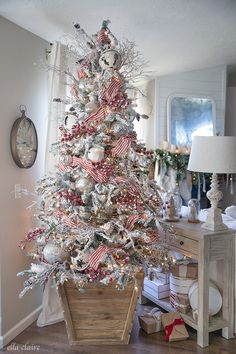 a white christmas tree with red, white and silver decorations in a living room area