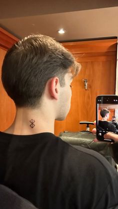 a man with a tattoo on his neck taking a selfie in front of a mirror