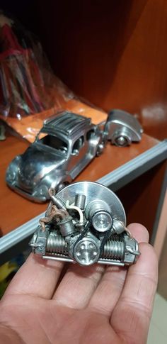 a hand holding a metal object in front of a shelf with other items on it