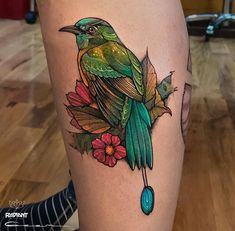 a bird sitting on top of a branch with leaves and flowers around its legs,