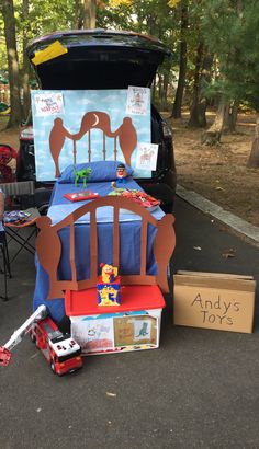 a child's bed and toys are on the ground next to an open trunk