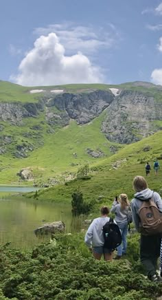 several people hiking up a hill near a body of water