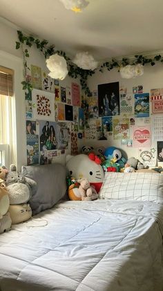 a bed with lots of stuffed animals on top of it in a room filled with posters