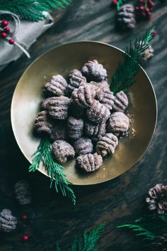 a bowl filled with powdered sugar and pine cones on top of a wooden table