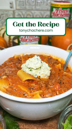 a white bowl filled with pasta and sauce on top of a wooden cutting board next to oranges