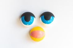 an odd looking face made out of plastic balls on a white surface with blue and yellow eyes