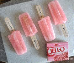 four popsicles sitting on top of a table next to a box of jello