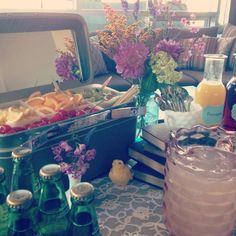 a table topped with lots of bottles and vases filled with flowers