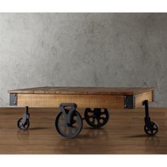 an old fashioned coffee table with wheels on the top and bottom, sitting on a wooden floor