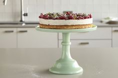 a cake sitting on top of a green cake stand in a kitchen next to an oven