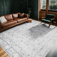 a living room with leather couches and a large rug on the floor in front of a window