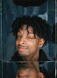 a man with dreadlocks looking at his reflection in the mirror while wearing a black shirt