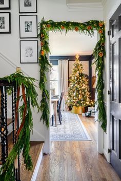 a christmas tree decorated with greenery in the entry way to a house that has been decorated for christmas