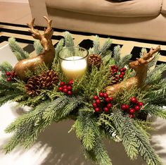 a christmas centerpiece with pine cones, berries and deer figurines on it