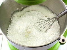 a mixing bowl filled with white flour and whisk on top of a green blender