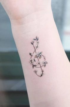 a small tattoo on the wrist of a woman's left arm, with flowers growing out of it