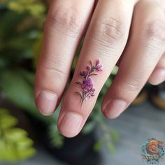 a woman's hand with a small flower tattoo on it, and the ring finger