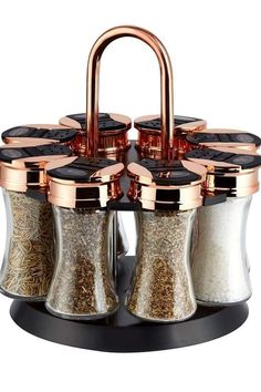 four spice dispensers on a black stand with copper accents and handles in the middle