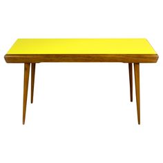 a yellow table sitting on top of a white floor next to a wooden frame and legs