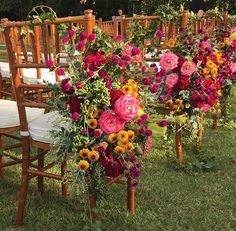 a bunch of chairs with flowers on them in the grass next to each other,