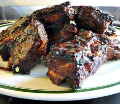 several pieces of meat sitting on top of a white plate with green trimmings