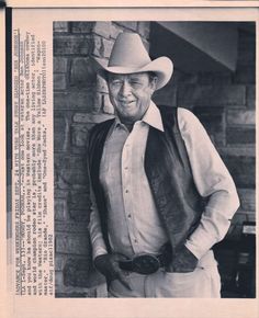 an old black and white photo of a man wearing a cowboy hat with his hands in his pockets