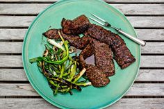 a green plate topped with meat and veggies on top of a wooden table