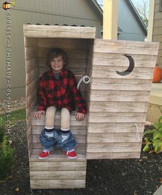 a young boy is sitting in a wooden box